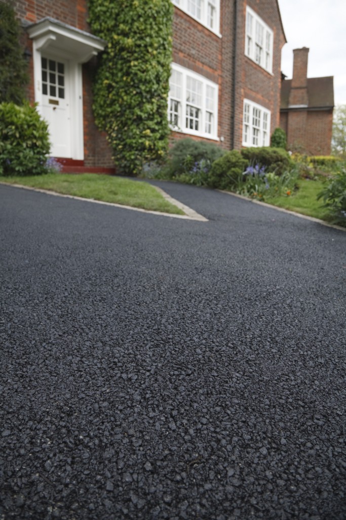 New asphalt tarmacadam driveway outside a beautiful brick house in London. Lots of copy space